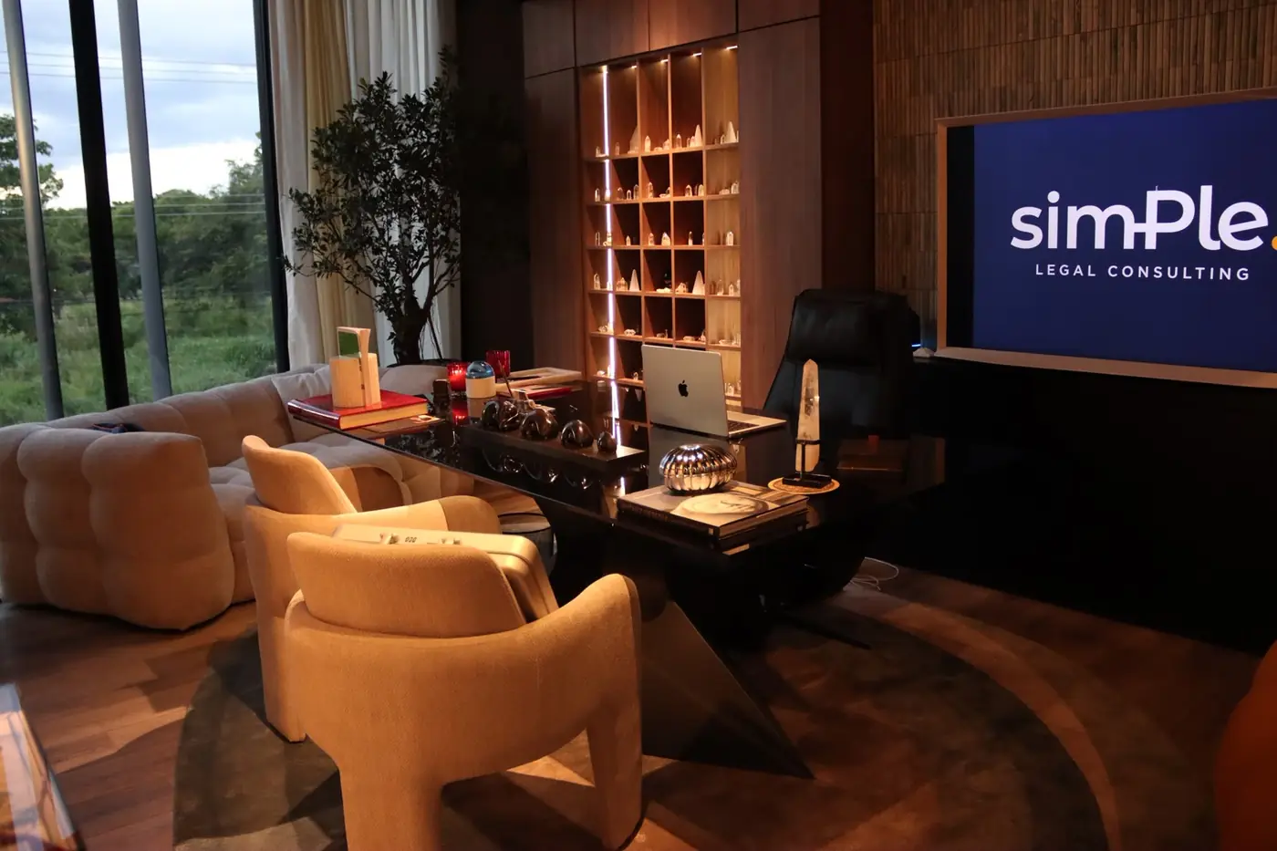 Office desk with a screen showing the firm wordmark and a view to green hills