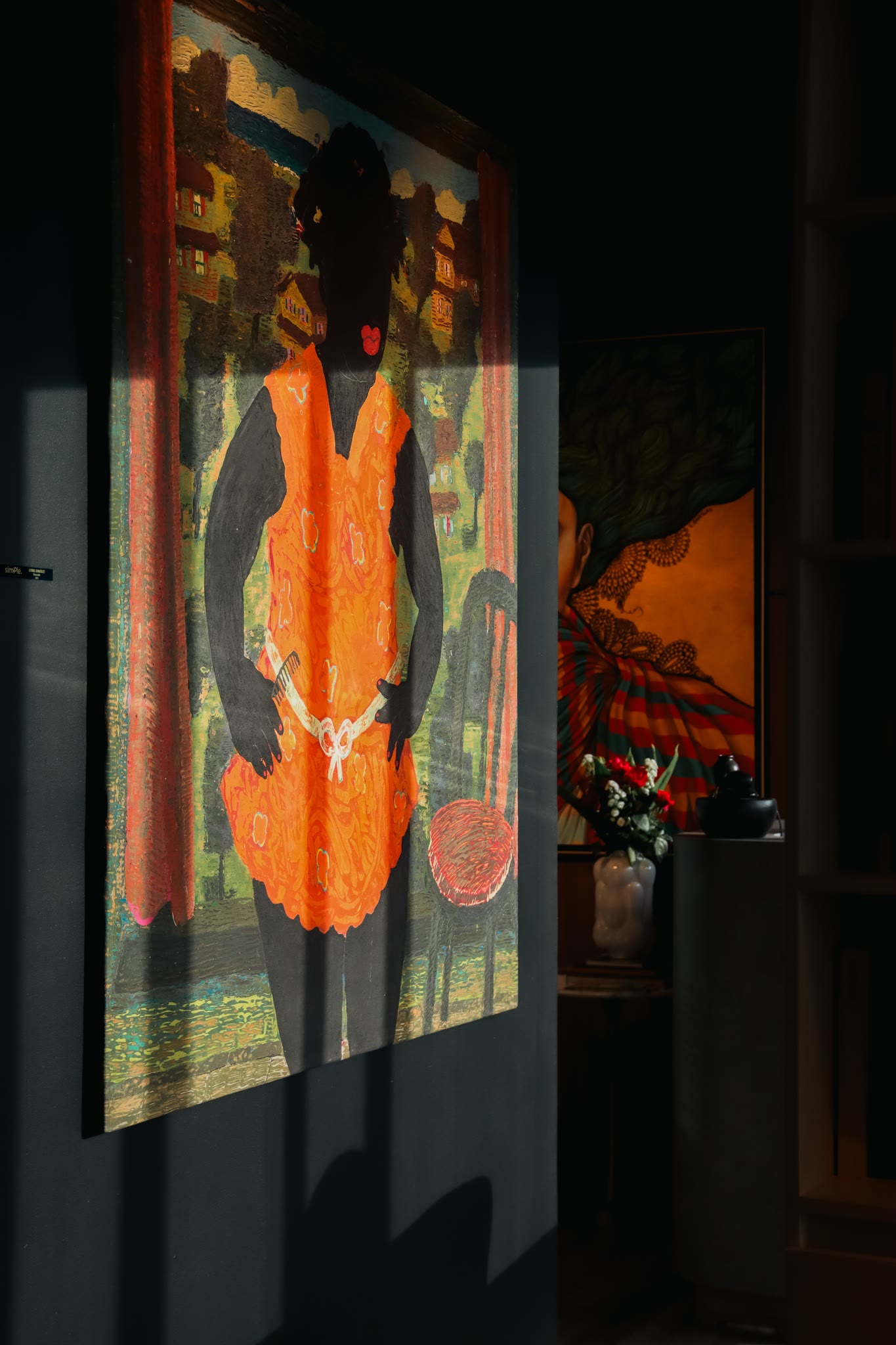Painting of a woman in an orange dress on a dark wall